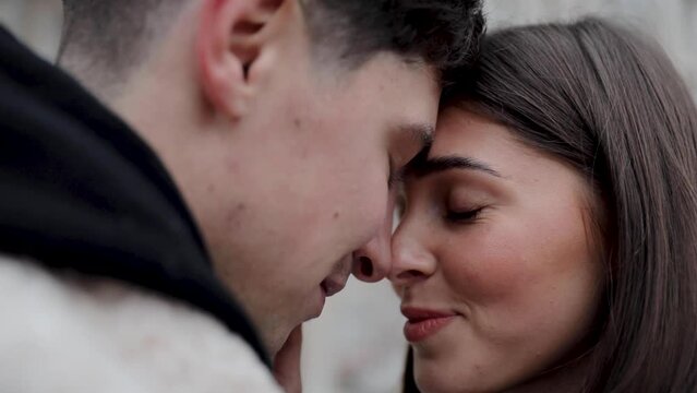 Man and woman touch noses of each other close up slow motion. Young happy smiling couple spend time together looking at each other with great love