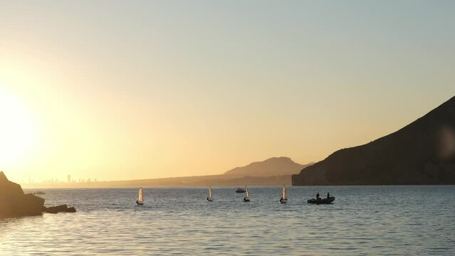 Sailors sport competition. Yacht club regatta in the open sea. Small yachts for training at sea. Yachting and sailing training. Summer sport. Athletes in the regatta. Calpe city, Spain.