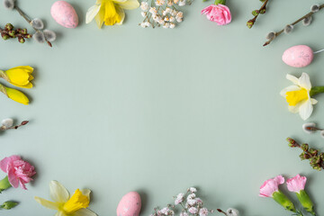 Fototapeta na wymiar Spring flowers ans easter eggs border on green background with copy space. Easter greeting card template