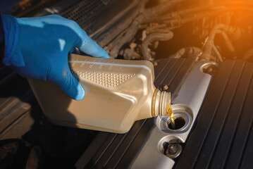 Man top up engine oil, check oil level. Pouring motor oil from plastic canister. Mechanic pouring...