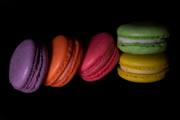 Heap of colorful macaroons on black background