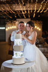 newlyweds happily cut and taste the wedding cake