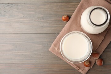 Glassware with lactose free milk and hazelnuts on wooden table, top view. Space for text