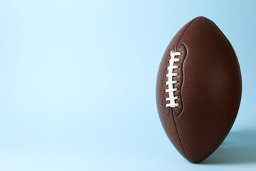 American football ball on light blue background. Space for text