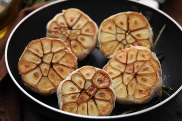 Frying pan with fried garlic on table, closeup