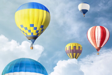 Many bright hot air balloons flying in sky