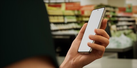Caucasian male using his smartphone during shopping in the supermarket
