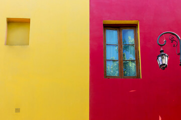 Colored walls in neighboring houses with wooden window and colonial lamp. 