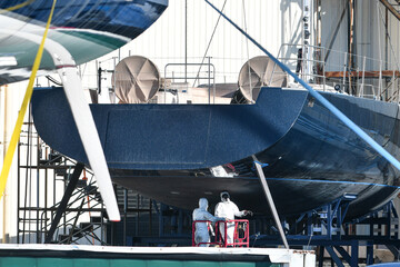 two technicians in overalls with respirators service a yacht