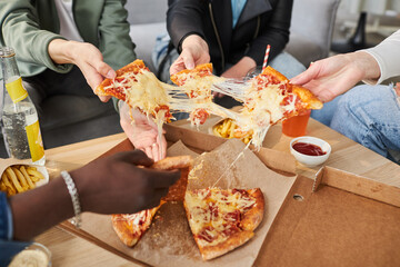 Close up shot multi-ethnic friends at table taking slices of delicious hot pepperoni pizza with...