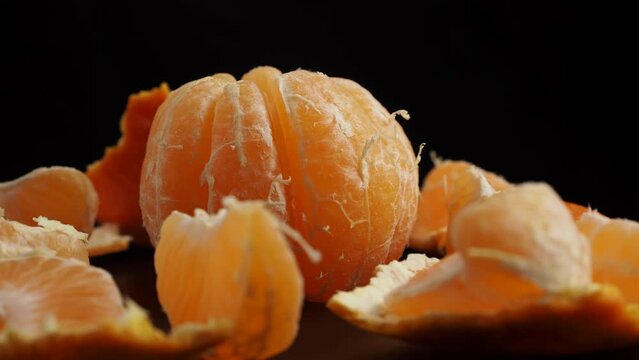 Rotating peeled tangerine on a black background. Tangerines close-up.