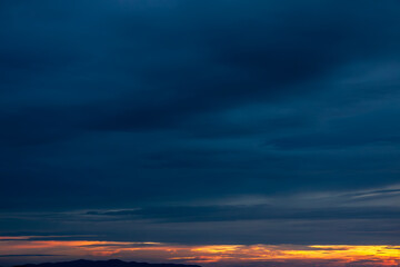 Naklejka na ściany i meble Last rays of sun on cinematic colorful contrast sunset sky with nobody on the horizon