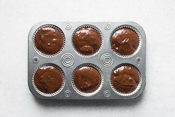 chocolate muffin batter into a cupcake tin, portioned muffin batter into a cupcake pan, process of making chocolate muffins