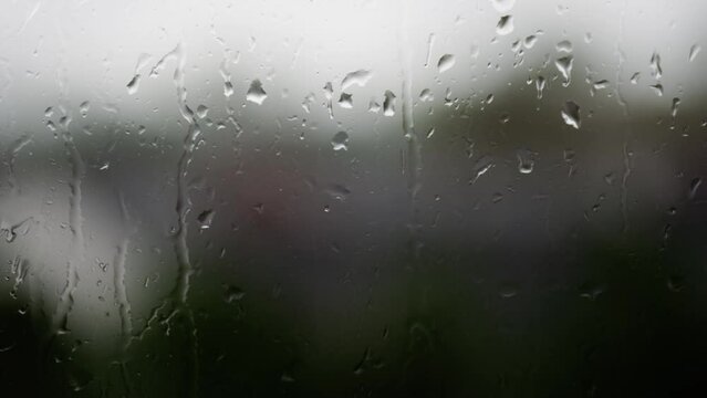 Mesmerizing raindrops gracefully cascading down the window on a rainy day, capturing the beauty of a tranquil and soothing atmosphere.