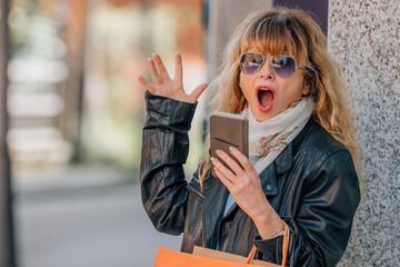 woman with shopping bags and mobile phone with expression of surprise and amazement