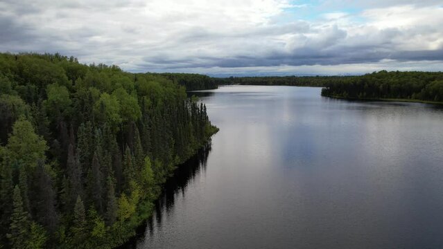 ALASKA - 2023 - Excellent aerial footage moving over a lake lined by green forests in Alaska.