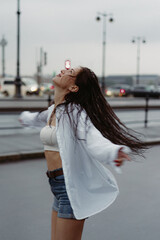 Obraz premium Woman walking down street in rainy weather in white shirt and blue jeans shorts