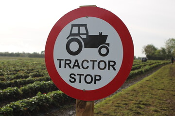 Round sign "Tractor Stop" with tractor symbol, taken outdoors in a field