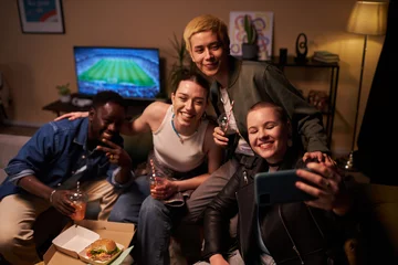 Foto op Plexiglas Medium full shot of four multi-ethnic young adults posing for selfie with fizzy drinks while gathering in living room for watching football match © Seventyfour