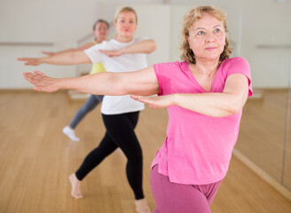 Elderly women doing stretching exercises warming up at dance class