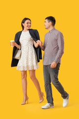 Lovely young couple holding hands on yellow background