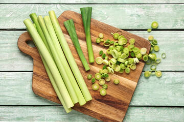 Board with slices of fresh leek on green wooden background
