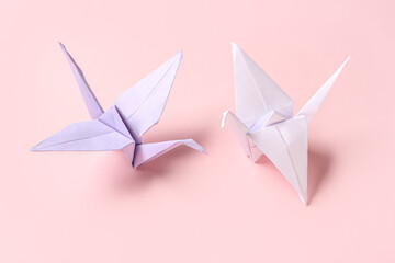 Origami cranes on pink background