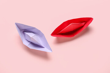 Colorful origami boats on pink background