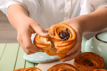 Woman eating tasty cruffins with chocolate at table