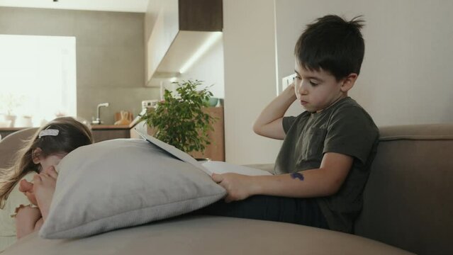 Little boy learing and writing alphabet looking very happy, sitting comfortable on sofa at home. Education, family and homework concept.
