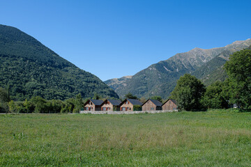 Wooden houses lined up next to each other in the Barruera Valley, surrounded by nature