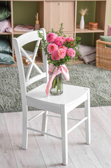Vase of beautiful pink dahlias on chair in living room
