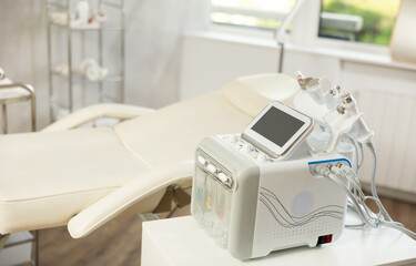Interior of clinics cosmetology room, equipped with modern tools and universal multifunctional beauty machine with six different nozzles for skin care procedures