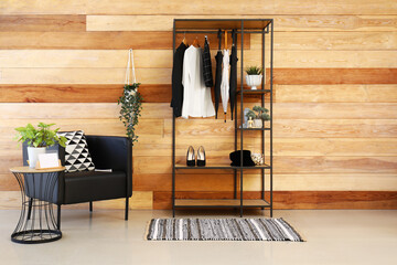 Rack with clothes, umbrellas and decor in interior of stylish room