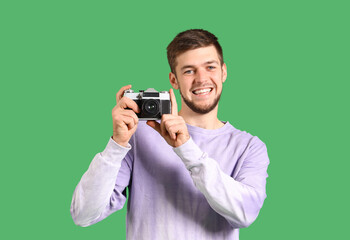 Young bearded man with photo camera on green background