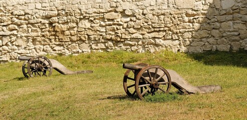 An old medieval cannon against the background of a fortress wall.