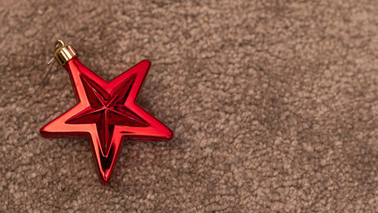 Fototapeta na wymiar Seasonal Decor: Red Star Ornament Creating Contrast on Brown Background