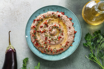 Plate of tasty baba ghanoush on green background
