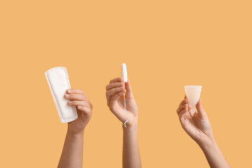 Female hands with different feminine hygiene products on color background