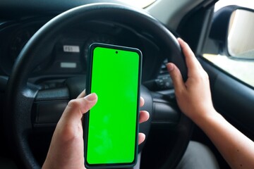 The green screen of the phone is chroma key in the car. Driver is sitting in the car and watching...