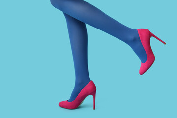 Legs of beautiful young woman in stylish high heels on blue background