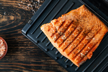 Grilled salmon fillets seasoned with salt, pepper, and herbs are cooked on a grill.