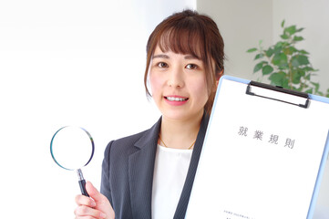 就業規則とルーペを持つ女性