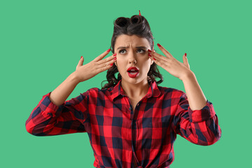 Upset young pin-up woman on green background