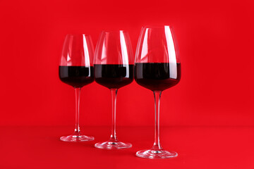 Glasses of red wine on color background