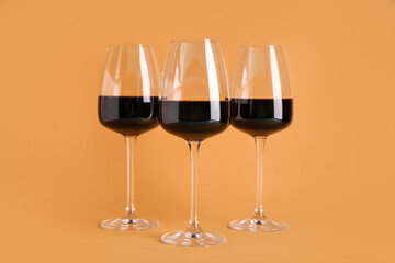 Glasses of red wine on orange background