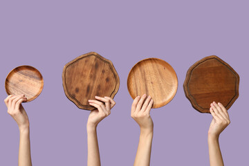 Female hands with wooden cutting boards on lilac background