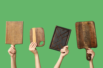 Female hands with wooden cutting boards on green background