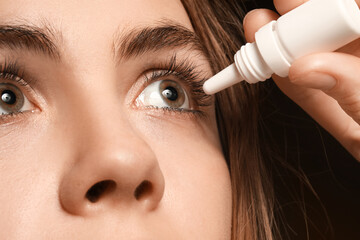 Young woman with hazel eyes using eye drops, closeup
