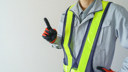 指差しポーズをする作業服の男性｜建設業・警備員・ガードマン　イメージ